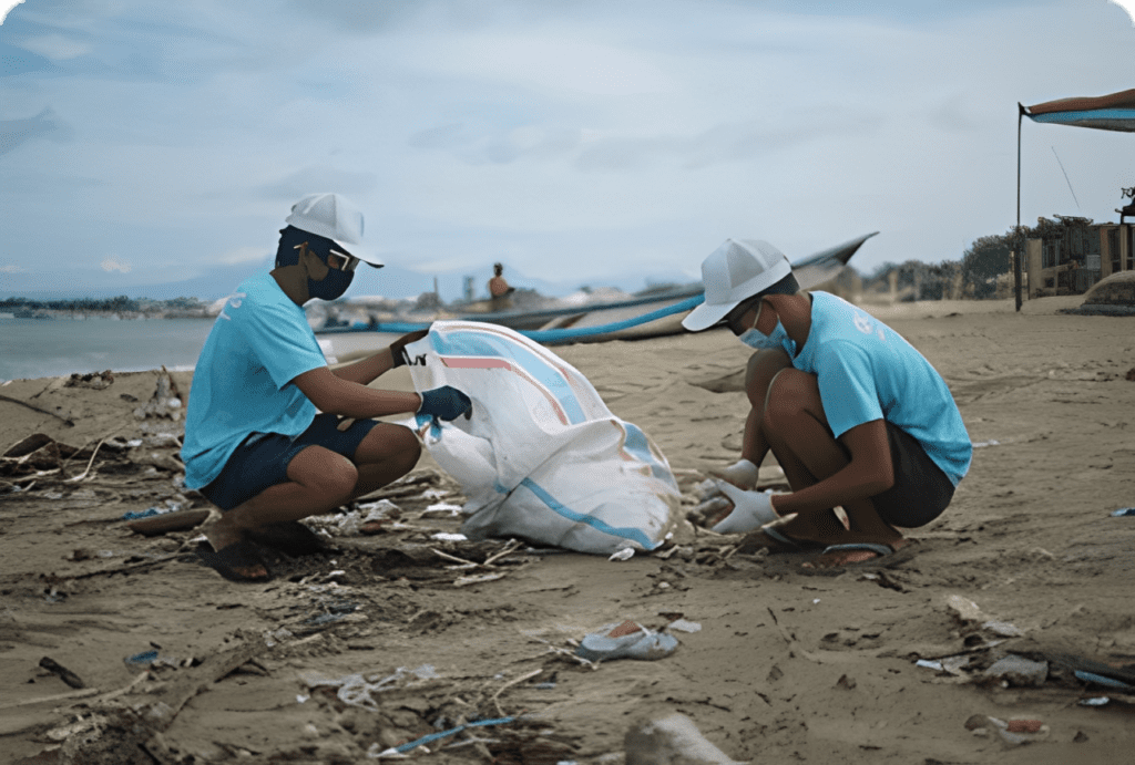 Two people picking up litter on sand